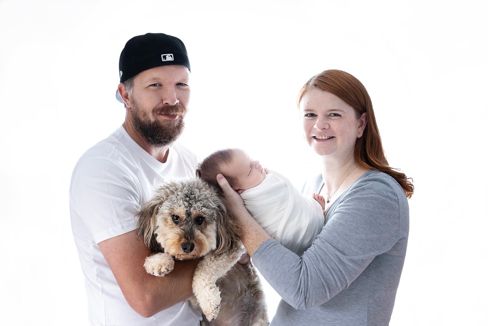 Happy family with newborn baby girl and dog in Witham studio, bright professional family photoshoot